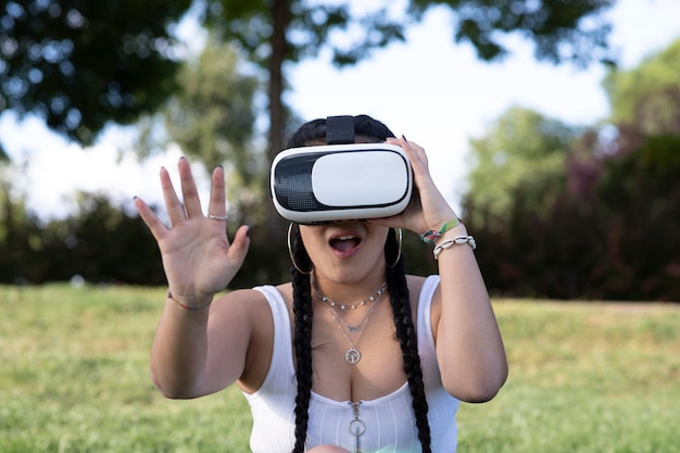 Bella ragazza utilizzando occhiali per realtà virtuale in un parco