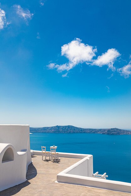 Bella scena di viaggio di coppia due sedie bianche sulla caldera, vacanza romantica isola di Santorini, Grecia