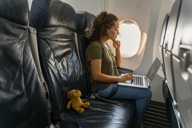 Bella signora adulta che guarda lo schermo del laptop in aereo