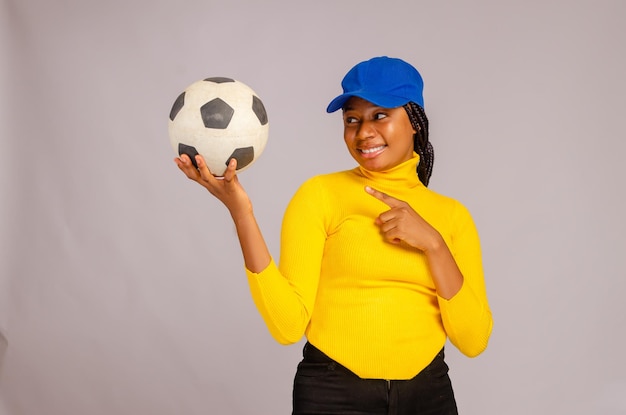 Bella signora africana sorridente mentre indica la palla sulla sua mano