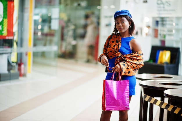 Bella signora afroamericana con borse della spesa nel centro commerciale.