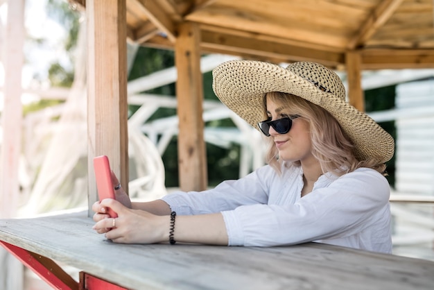 Bella signora che tiene la cella e che fa selfie vicino al gazebo in legno al caldo giorno d'estate