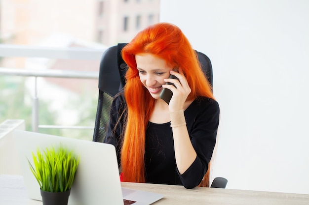 Bella signora di affari che lavora con il computer portatile in ufficio.