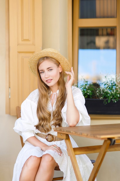 Bella signora in abito bianco si siede sulla terrazza