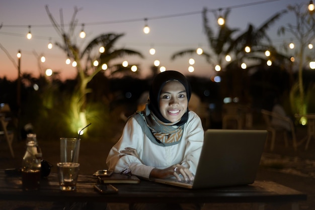 Bella signora musulmana asiatica abbigliamento casual che lavora utilizzando il computer portatile di notte