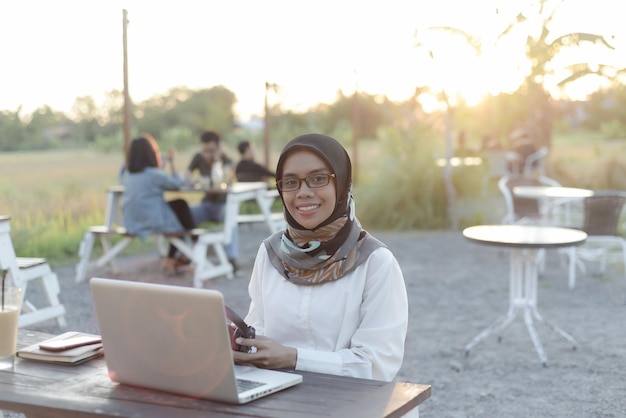 bella signora musulmana asiatica abbigliamento casual che lavora utilizzando il computer portatile