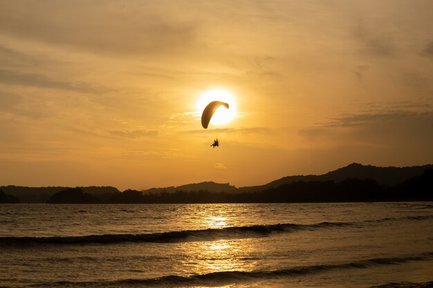 Bella silhouette di volo in aliante nel cielo del tramonto sulla spiaggia.