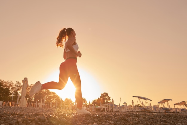 Bella silhouette donna sportiva in abiti sportivi fare jogging all'alba del mattino