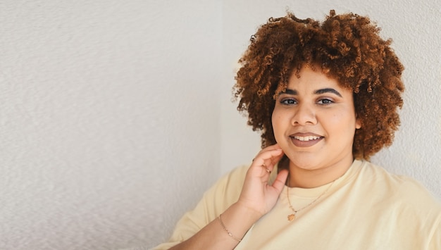 Bella sorridente felice curvy plus size donna nera africana capelli afro con trucco in posa in beige