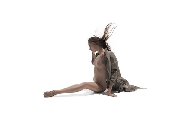 Bella sottile giovane femmina moderna jazz stile contemporaneo ballerina in silhouette indossando beige lungo mantello isolato su uno sfondo bianco studio