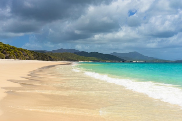 Bella spiaggia tropicale con onde dolci e schiuma bianca sul fondo sabbioso della riva estiva.