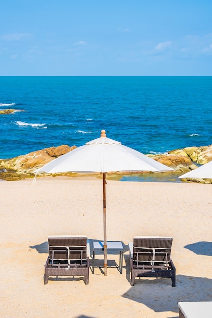 Bella spiaggia tropicale mare con ombrellone e sedia intorno a nuvola bianca e cielo blu per viaggi di vacanza