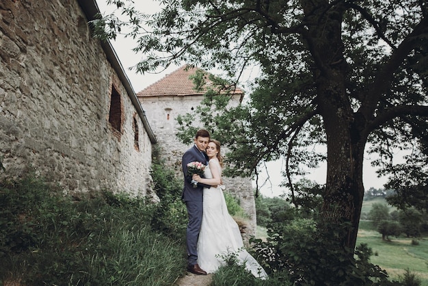 Bella splendida sposa e sposo che baciano felici sposi che abbracciano e abbracciano al vecchio castello momenti romantici felici concetto di fuga amore sensuale spazio per il testo