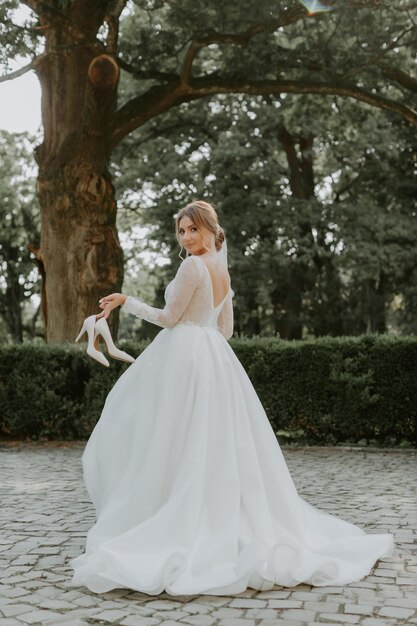 Bella sposa alla moda in posa vicino al vecchio muro del castello