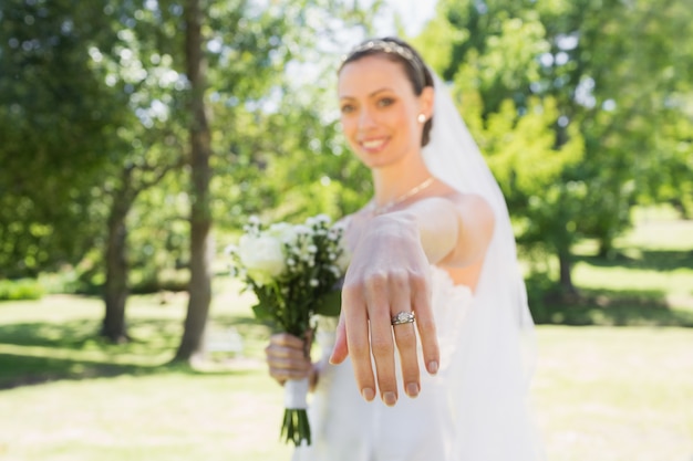 Bella sposa che mostra fede nuziale in giardino