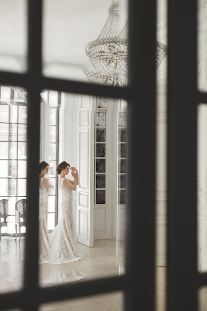 Bella sposa che posa in vestito da sposa in uno studio bianco della foto