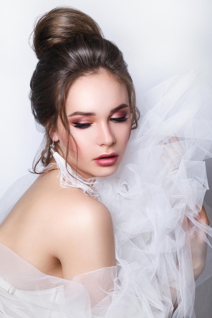 Bella sposa con acconciatura da sposa di moda su sfondo bianco