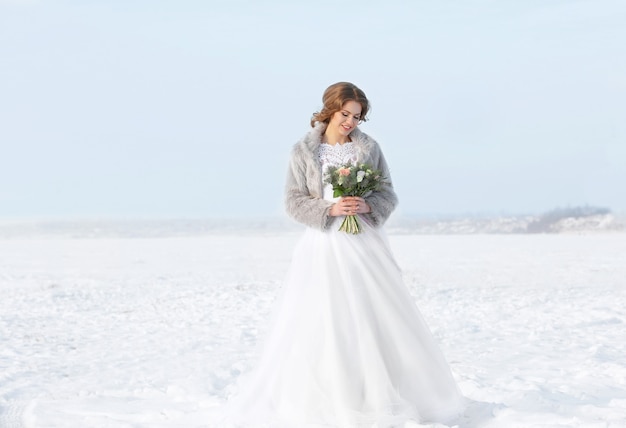 Bella sposa con bouquet all'aperto il giorno d'inverno