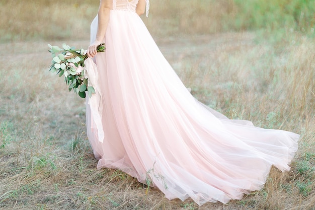 Bella sposa con bouquet e abito con strascico nella natura. fotografia d'arte.