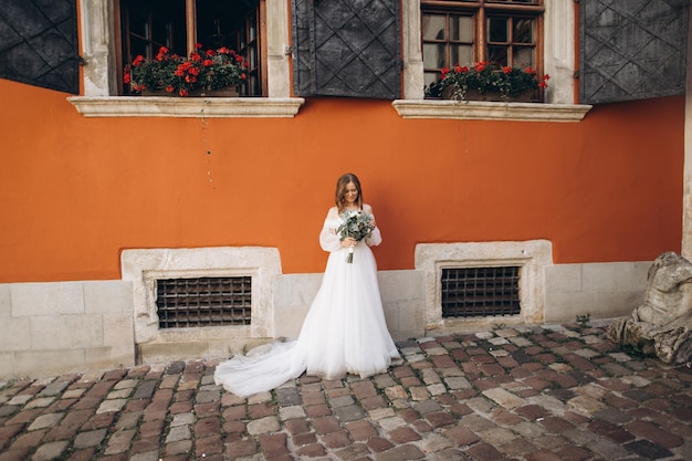 Bella sposa con un bouquet in posa per le strade della città