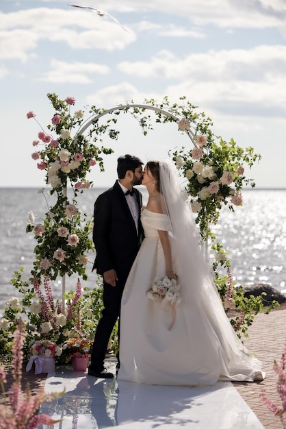 Bella sposa e sposo durante una cerimonia di matrimonio all'aperto su una spiaggia vicino al mare. Luogo perfetto