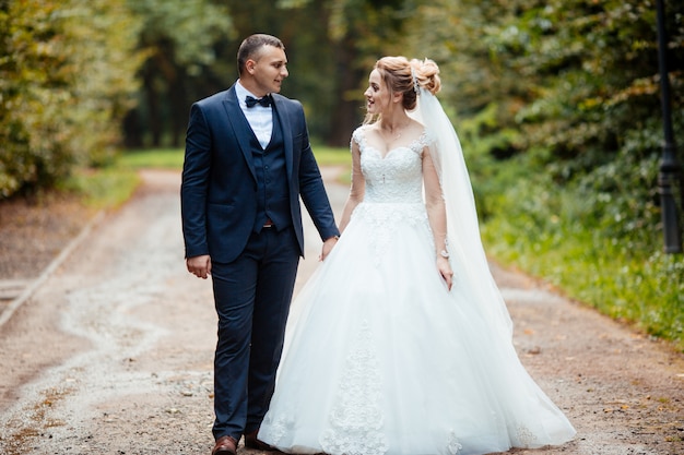 Bella sposa e sposo elegante di giorno delle nozze che camminano dopo il lusso di nozze