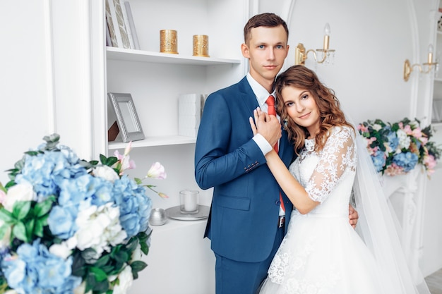 Bella sposa in abito bianco e lo sposo in tuta, in posa in bianco Studio interno, matrimonio