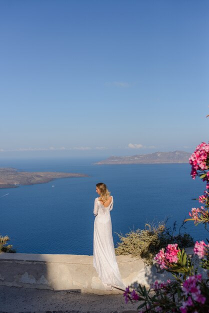 Bella sposa in abito bianco in posa sullo sfondo del Mar Mediterraneo a Thira, Santorini.