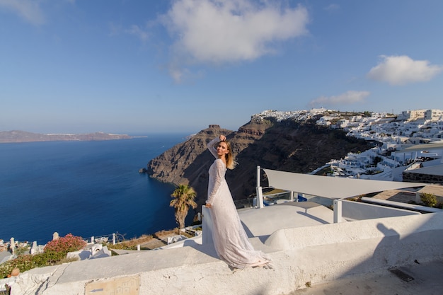 Bella sposa in abito bianco in posa sullo sfondo del Mar Mediterraneo a Thira, Santorini.