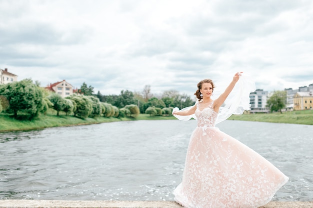 Bella sposa in abito da sposa con velo sul viso in posa all'aperto con il lago sullo sfondo