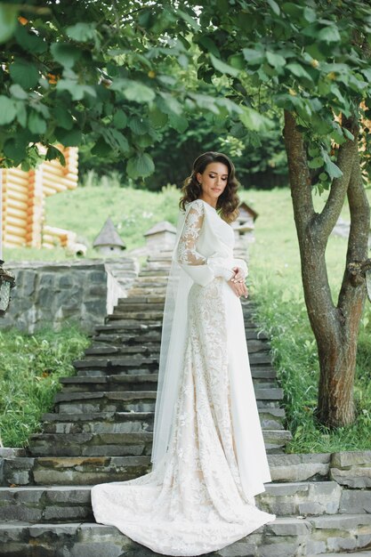 Bella sposa in abito da sposa di moda su sfondo naturale.