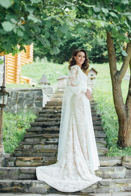 Bella sposa in abito da sposa di moda su sfondo naturale.