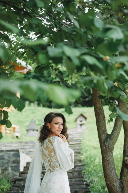 Bella sposa in abito da sposa di moda su sfondo naturale.