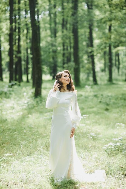 Bella sposa in abito da sposa di moda su sfondo naturale.