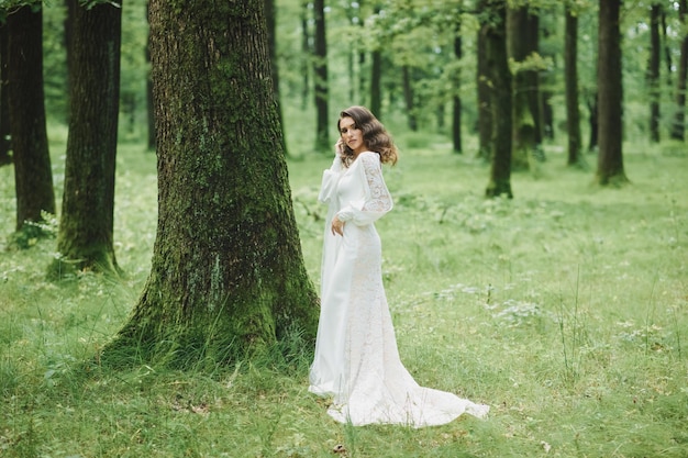 Bella sposa in abito da sposa di moda su sfondo naturale.