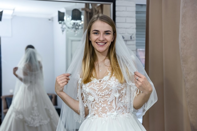 Bella sposa in abito da sposa in posa davanti allo specchio