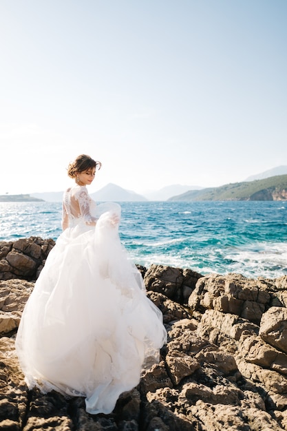 Bella sposa in abito da sposa tenero sulla spiaggia rocciosa dell'isola di Mamula.