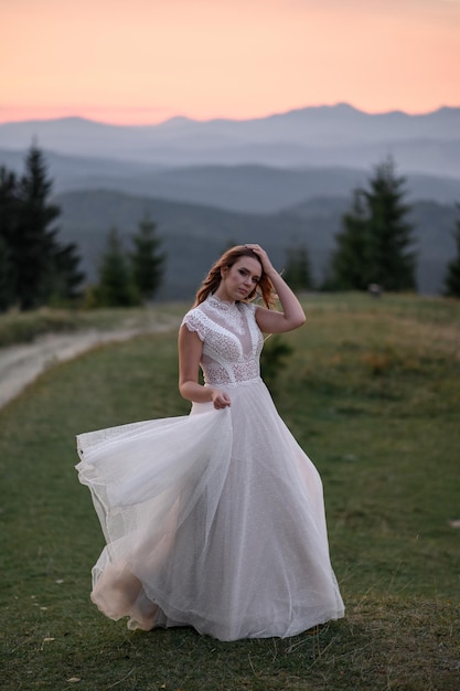 Bella sposa in un abito da sposa bianco su uno sfondo di montagne