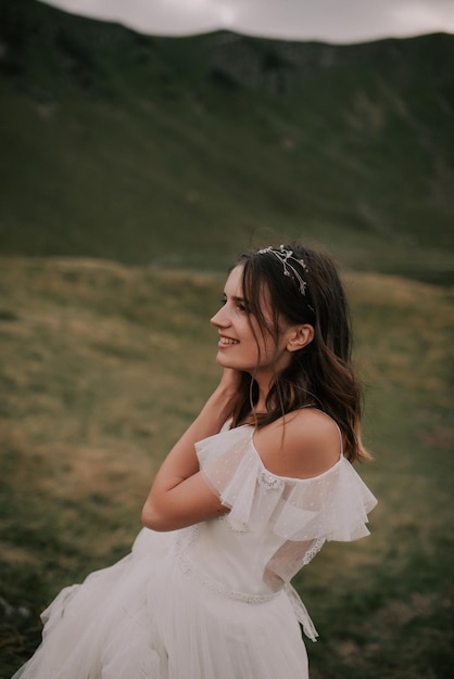 Bella sposa in un abito da sposa bianco su uno sfondo di montagne