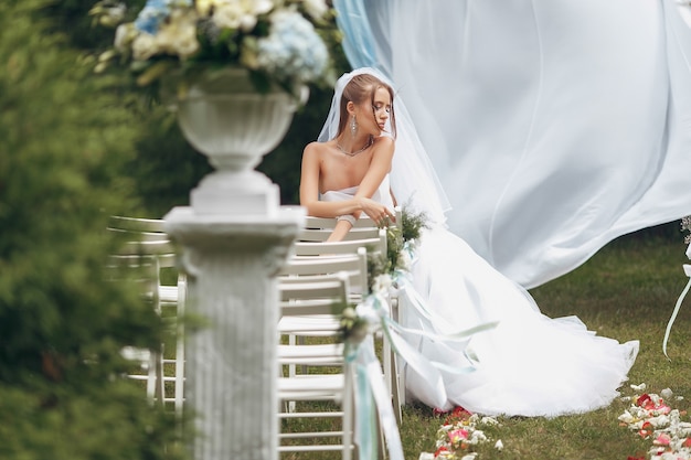 Bella sposa in un magnifico abito da sposa in posa tra il verde sulla strada