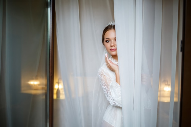 Bella sposa in una mattina di nozze in accappatoio e velo