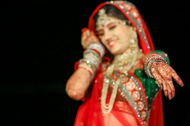 Bella sposa indiana che mostra la mano di Mehndi che indossa sari e gioielli d'oro al matrimonio indiano