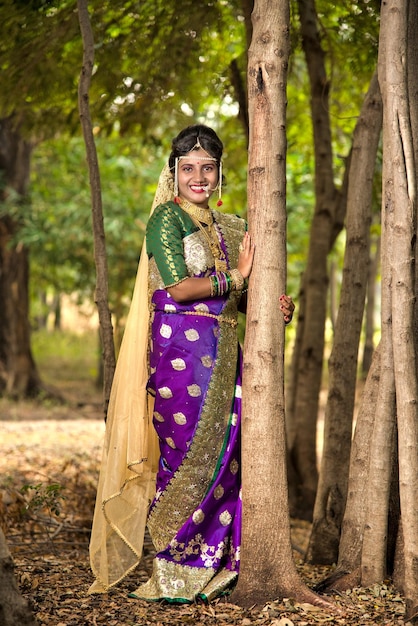 Bella sposa indiana in saree tradizionale che posa all'aperto nel parco