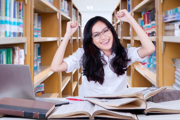 Bella studentessa che alza le mani in biblioteca