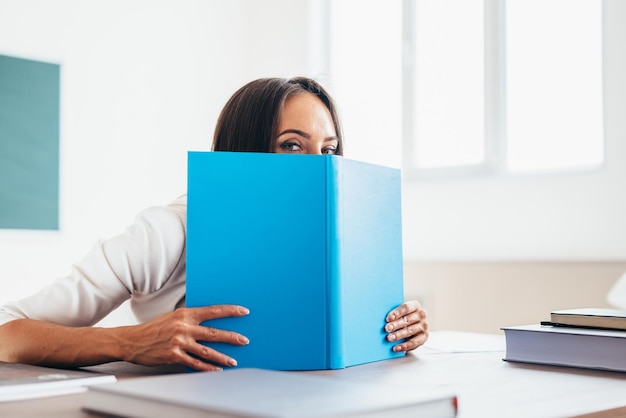 Bella studentessa che si nasconde dietro il libro