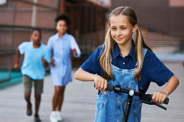 Bella studentessa con due code di cavallo in sella a uno scooter elettrico