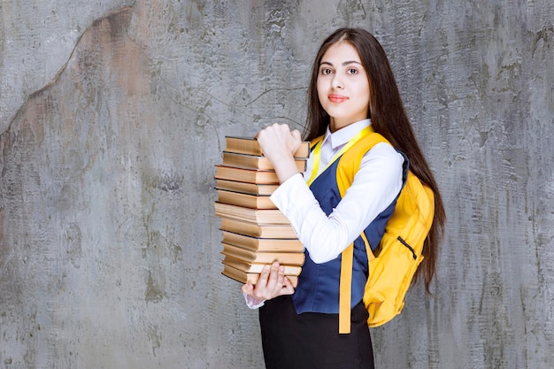 Bella studentessa con libri in piedi e in posa. Foto di alta qualità