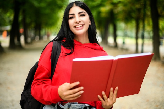 Bella studentessa in possesso di un libro all'aperto