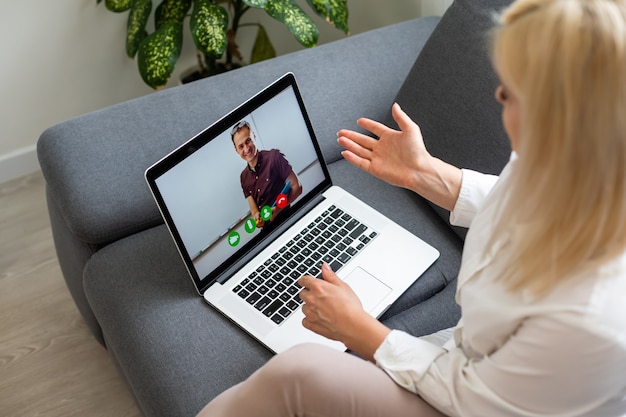 Bella studentessa sorridente che utilizza il servizio di formazione online. Giovane donna che guarda nel display del computer portatile guardando il corso di formazione e ascoltandolo con le cuffie. Moderno concetto di tecnologia di studio