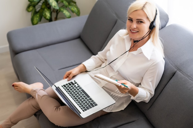 Bella studentessa sorridente che utilizza il servizio di formazione online. Giovane donna che guarda nel display del computer portatile guardando il corso di formazione e ascoltandolo con le cuffie. Moderno concetto di tecnologia di studio